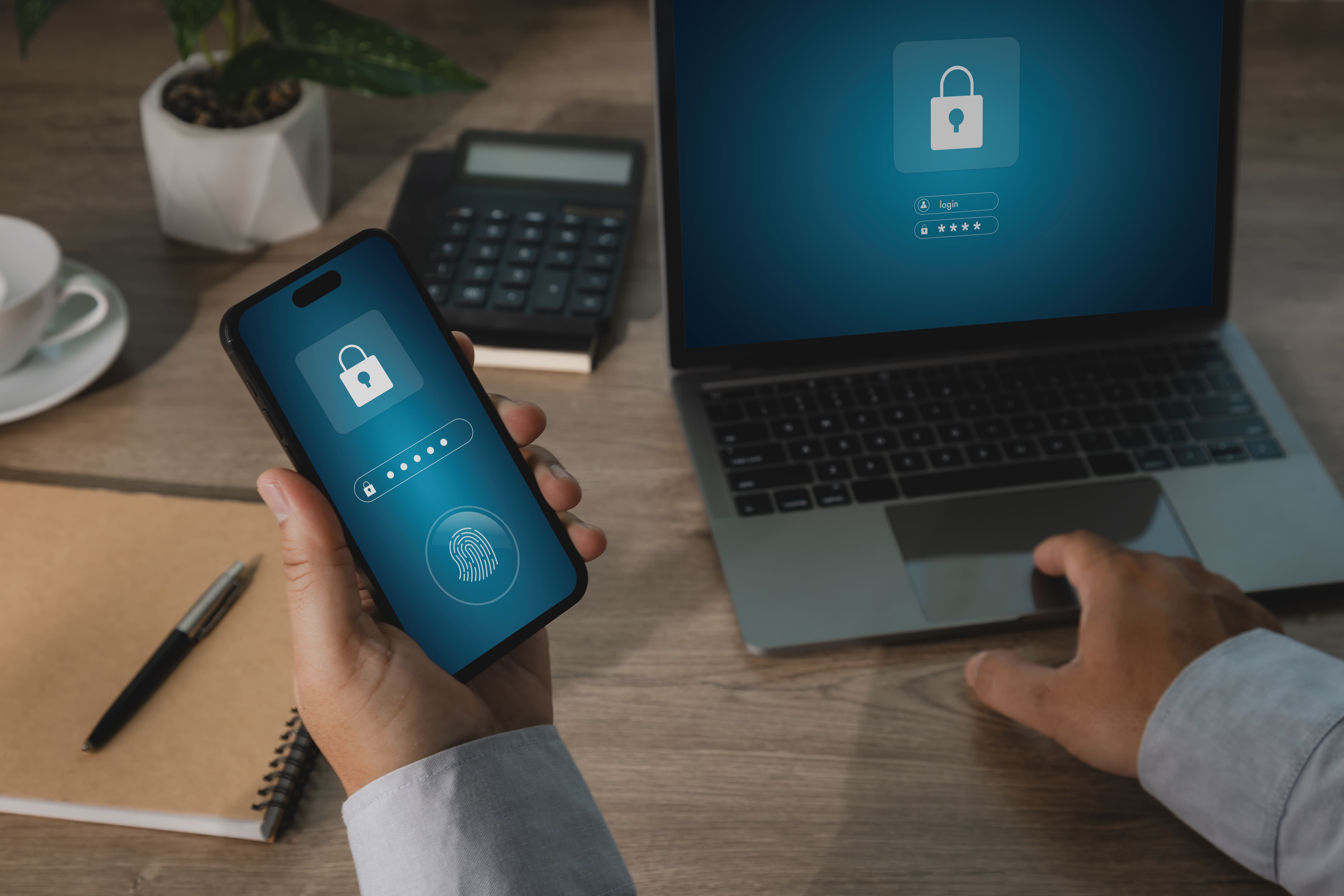 hand holding smartphone with cybersecurity login interface beside laptop displaying secure access sc1